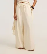 Pantalón pantalona color beige, confeccionado en viscolino con elástico y lazo ajustable en la cintura, de corte amplio y fluido.