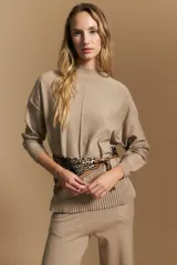 Polera de tejido de punto color marrón, con cuello alto y diseño de líneas verticales en el frente que aportan estructura. Presenta un calce relajado y mangas largas con puños ajustados.