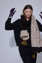 Chal rectangular de lana con diseño de patrón paisley y detalles geométricos. Presenta una combinación de colores en tonos tierra, marrón y beige, con terminaciones en pompones de lana color verde oliva en los extremos.