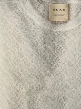 Sweater de punto calado confeccionado en 100% mohair italiano, con cuello redondo y mangas largas. Presenta una textura aireada y delicada con un diseño etéreo y sofisticado.
