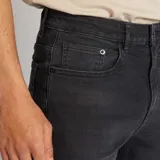 Pantalón jean de corte slim color gris oscuro, con bolsillos delanteros y traseros, y cierre con cremallera y botón.