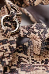 Sandalias de cuero color marrón chocolate, con tira ancha sobre el empeine con detalle de hebilla trenzada plateada, pulsera al tobillo con hebilla metálica y taco bajo cuadrado.