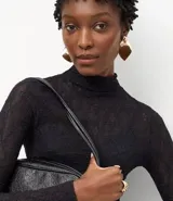 Blusa de encaje negro con cuello alto y mangas largas, de corte ajustado y diseño con transparencias.