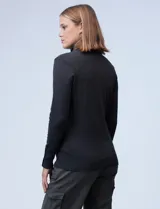 Polera gris de tejido fino con cuello alto y mangas largas con aplique de botones en los puños.