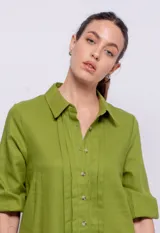 Vestido largo negro de lino y viscosa, abotonado al frente con alforzas en la parte central, mangas largas con elástico en los puños y cuello camisero.