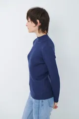 Polera de tejido morley color azul, con cuello alto y mangas largas, de corte ajustado al cuerpo.