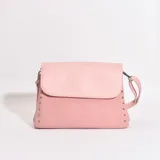 Bandolera rosa con solapa superior y tachas plateadas en los laterales.