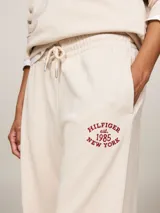 Pantalón de jogging color beige, de corte holgado, con cintura elástica ajustable con cordón y logo bordado en rojo.