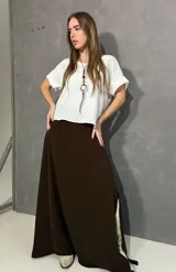 Falda larga marrón, de corte evasé, confeccionada en viscosa y elastano con pretina frontal y elástico trasero.
