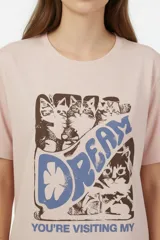 Remera de manga corta color blanco, de corte holgado con cuello redondo a la base y estampado frontal en tono bordó de un gato y un ovni en un paisaje desértico.