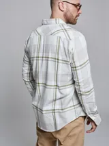 Camisa de manga larga confeccionada en algodón, con diseño de cuadros en tonos blanco y verde oliva. Presenta cuello clásico con botones y cierre frontal abotonado.