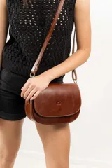 Cartera bandolera de cuero natural color marrón, con estructura rígida, costuras a la vista y logo grabado en el frente.