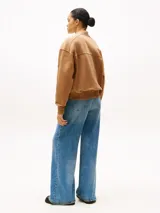 Buzo bomber color marrón confeccionado en felpa de algodón regenerativo, con cierre de cremallera, cuello, puños y ruedo acanalados. Presenta el logo de Tommy Hilfiger bordado en el pecho y en el puño.