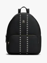 Mochila de diseño minimalista con acabado granulado, confeccionada en poliuretano. Presenta un compartimento principal con cierre de cremallera, un bolsillo exterior frontal con cierre, asa superior y correas ajustables. Incluye un detalle de cinta distintiva tonal en la parte delantera y el monograma TH metálico.