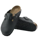 Zuecos Birkenstock modelo Boston, de cuero negro con tira ajustable y hebilla metálica, plantilla de corcho y suela de goma.