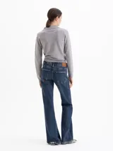 Jeans corte bootcut de tiro medio-bajo, confeccionado en denim azul con lavado desgastado y contrastes. Presenta cierre frontal con botón metálico y bolsillos laterales y traseros.