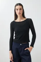 Remera de manga larga, color blanco roto, con cuello bote y textura acanalada. Presenta un efecto de doble capa o transparencia sutil en el escote.