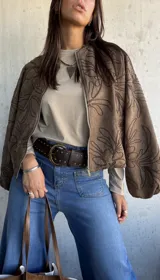 Remera de algodón color beige, de manga larga y cuello redondo, con detalle de tachas metálicas en los hombros.