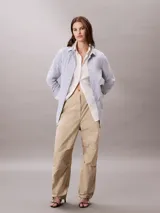 Pantalón parachute Calvin Klein de nailon suave con diseño holgado (loose fit), cintura elástica con cordón interior y cierre de botón y cremallera. Presenta bolsillos superpuestos y puños ajustables con cordón y cremallera.