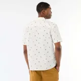 Camisa de manga corta color blanco con diseño estampado de pequeñas palmeras negras, cuello camisero y cierre frontal de botones.
