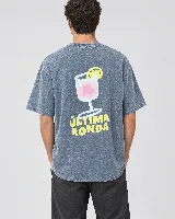 Remera de algodón gris con efecto acid wash, corte recto y mangas cortas. Presenta un estampado en la espalda de un trago en copa con la leyenda "Última Ronda" en color amarillo.