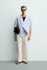 Camisa tipo kimono de corte relaxed fit, color celeste, confeccionada en tejido fluido de viscosa y lino. Presenta cuello con solapas de muesca, manga corta y cierre frontal cruzado con doble botonadura.