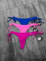 Bombacha de bikini tipo colaless con laterales regulables mediante lazos. Se presenta en cinco colores: naranja, negro, lila, amarillo flúor y blanco, y rojo.
