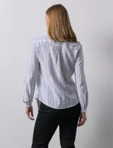 Blusa de lino estampada a rayas verticales en tonos blanco, verde, violeta, amarillo y rosa. Cuello a la base con escote en V y abertura central con botones. Delantera con bolsillos de parche. Mangas largas regulables con presilla y botón.