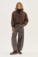 Bota de caña media confeccionada en cuero vacuno texturizado color marrón oscuro. Presenta un diseño minimalista con costuras reforzadas, tirador trasero y una suela de plataforma plana con capas en tonos beige, negro y suela.