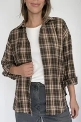 Camisa de manga larga con estampado de cuadros en tonos marrones y beige, confeccionada en una mezcla de algodón y poliéster. Presenta un diseño de corte holgado con cuello clásico y cierre frontal de botones.