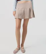 Short pollera de tiro alto en color beige, con diseño de sastrería, tablas delanteras y ruedo asimétrico.