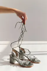Sandalias de cuero plateado con taco bloque, tiras finas y cordones para atar al tobillo.