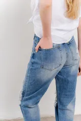 Jean azul de tiro medio y calce relaxed, con roturas amplias y desflecadas.