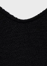 Malla enteriza de color negro con textura acanalada, diseño de cuello redondo y tirantes finos. Presenta una abertura en la espalda y forro interior.