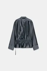 Blusa fluida cruzada de diseño envolvente, color gris oscuro satinado, con mangas largas y puños anchos. Cuenta con cuello mao y cordón ajustable en la cintura con lazada lateral.