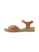 Sandalia plana de cuero color tostado con pulsera ajustable al tobillo y suela revestida en yute trenzado.