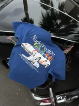 Remera azul marino de manga corta de la marca Nude Project, con cuello redondo y diseño gráfico en la espalda que incluye un auto deportivo en llamas, un perro dálmata y texto descriptivo.