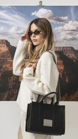 Cartera estructurada de tamaño mediano, confeccionada en símil cuero color negro. Presenta doble asa de mano, correa larga ajustable y desmontable, y un bolsillo trasero con cierre. El compartimento principal cuenta con cierre, división interna y bolsillos organizadores.
