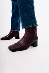 Bota de caña media con textura de reptil en color negro, punta cuadrada y taco bloque.