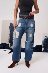 Jean de tiro medio con corte recto y holgado, confeccionado en denim azul con detalles de roturas y desgastes. Cuenta con cierre frontal, botón metálico y bolsillos funcionales.