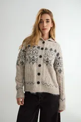 Saco de punto con cuello tipo polo, cierre frontal de botones oscuros y diseño de estampado jacquard en tonos grises y beige. Presenta mangas largas con puños acanalados y textura suave.