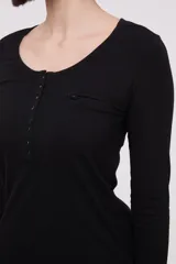 Remera blanca de manga larga, entallada, con cuello redondo y una hilera de botones en el frente. Incluye un pequeño bolsillo decorativo en el pecho.