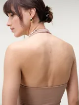 Top halter cropped de tejido rib color beige, con escote redondo pronunciado y espalda descubierta, de calce entallado.