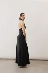 Vestido largo negro de corte al cuerpo con cuello halter y detalle de hebilla metálica dorada en el hombro con tira drapeada.