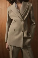 Blazer entallada de Zara Woman Collection, confeccionada en tejido con lana. Presenta cuello con solapas de muesca, cierre frontal cruzado con botones y manga larga con detalle de botones en los puños.