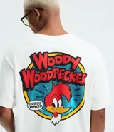 Remera boxy de algodón color blanco, con cuello redondo y mangas cortas. Presenta un estampado grande en la espalda del personaje El Pájaro Loco, con su nombre en rojo y un fondo azul y amarillo, y un globo de diálogo que dice "Guess Who?".