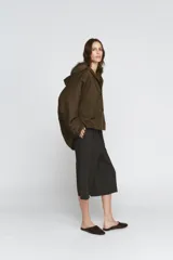 Trench corto de corte recto con capucha y cuello desmontable efecto pelo. Presenta cierre frontal con botones, bolsillos laterales y mangas largas con trabillas en los puños.