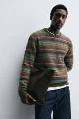 Jersey de punto con diseño jacquard geométrico de rayas horizontales en tonos tierra, verde y naranja. Presenta cuello redondo, manga larga y terminaciones en rib acanalado.