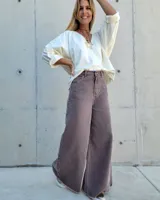 Pantalón de jean color beige, de corte recto y tiro alto, con ruedo deshilachado y cierre frontal con botón y cremallera.