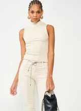 Blusa beige de cuello alto y corte ajustado, sin mangas y confeccionada en tejido de punto acanalado.